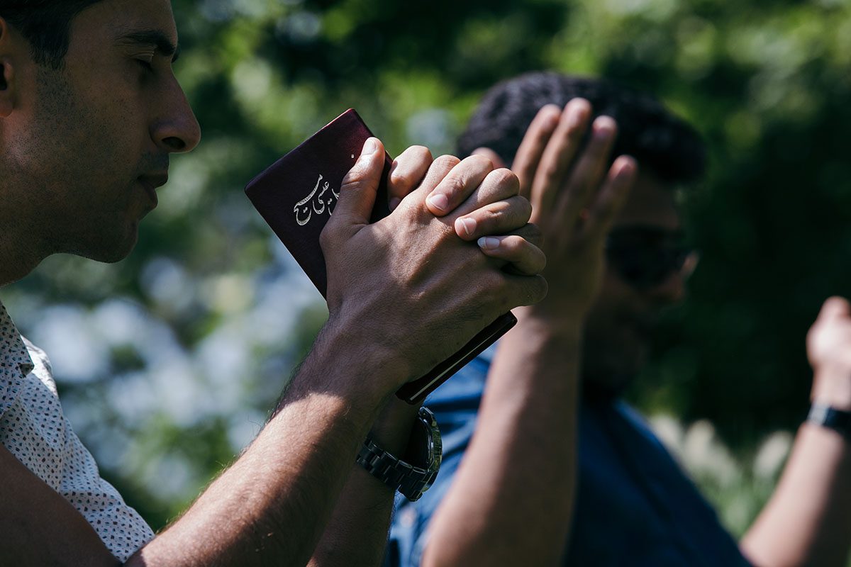 Iranian man praying and holding his Bible